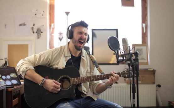Estudio de grabación acústico con guitarra y micrófono preparados para sesión